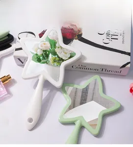 Close-up of star-shaped handheld makeup mirrors in white and green with hanging holes