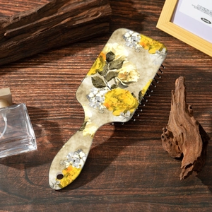 Detail of vintage yellow rose pattern on a wide-handle anti-static air cushion comb