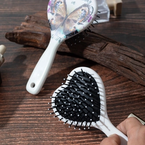 Vintage white bow air cushion hairbrush with butterfly design on a rustic wooden background