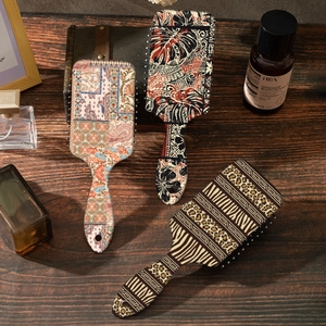 Bohemian leopard print and floral pattern air cushion hairbrushes on a wooden table