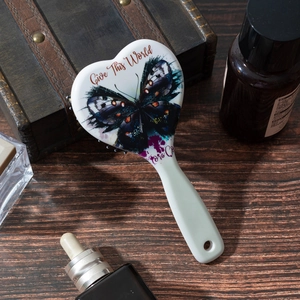 Detail of heart-shaped massage hairbrush with blue butterfly print and ergonomic handle