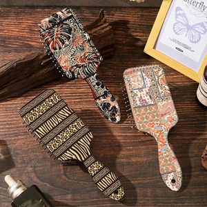 Artistic leopard and bohemian print air cushion hair brushes on vintage wooden desk