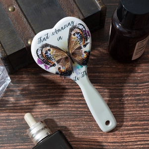 Close-up of heart-shaped massage comb with colorful butterfly print on wood surface