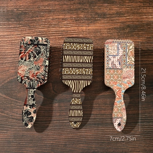 Three bohemian air cushion hairbrushes with leopard and floral prints on wood background
