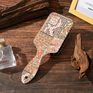 Detail of bohemian paisley print hairbrush with air cushion on dark wood background