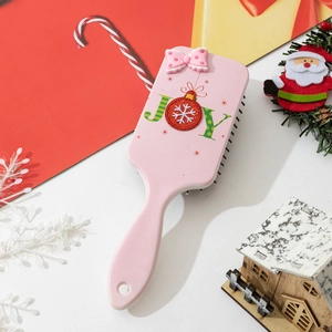 Detail of pink air cushion hairbrush with JOY text and festive Christmas decorations