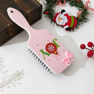 Pink bow hair brush with Joy lettering and snowflake pattern in Christmas setting
