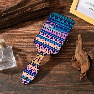 Detail of bohemian air cushion hairbrush with vibrant geometric patterns on wood background