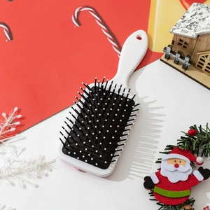 Bowtie air cushion massage hairbrush with white handle in a festive Christmas setting