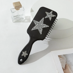 Détail d'une brosse à cheveux noire avec des étoiles brillantes en strass élégants