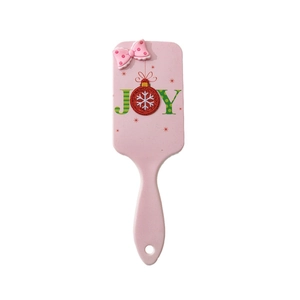 Pink air cushion hairbrush with bow detail and festive JOY print on white background