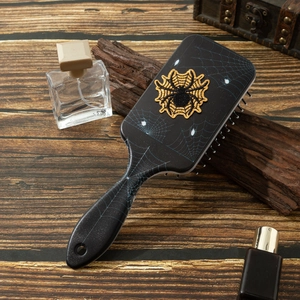 Detail of a black hairbrush featuring a spider web print and embroidered spider patch