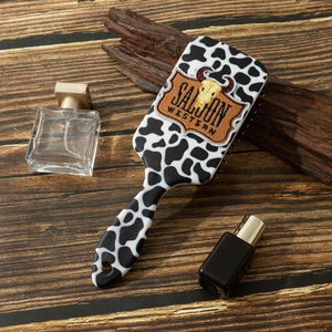 Détail d'une brosse à cheveux à motif vache avec broderie tête de taureau sur fond bois