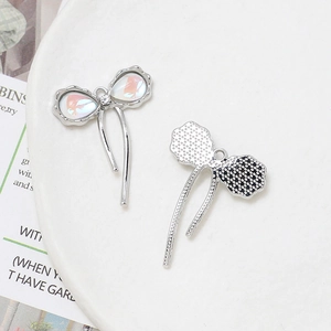 Detail of silver alloy bow pendants with iridescent inlay and fine mesh texture back