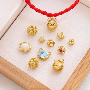 Colgante de gato dorado con ópalo y pulsera trenzada roja en un joyero de madera