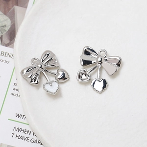 Macro detail of silver bow pendants with white enamel hearts for DIY jewelry