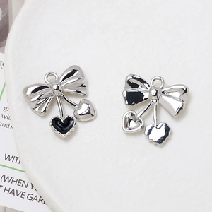 Detailed view of silver bow and black enamel heart pendant for DIY jewelry making
