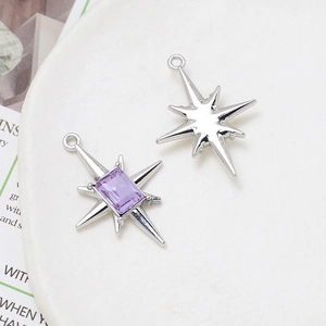 Detail of silver octagonal star pendants with a purple rectangle gemstone on a plate