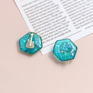 Dettaglio del ciondolo esagonale in resina con glitter blu e mini chitarra dorata