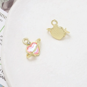 Macro detail of planet-heart pendant showing pink pearlescent finish and gold alloy back