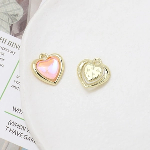 Macro detail of heart-shaped alloy pendant with pink crystal and golden filigree frame