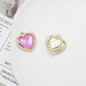 Detailed view of alloy heart charms with pink resin inlay and gold textured finish for DIY