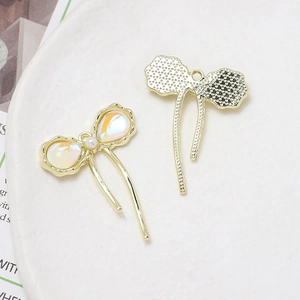 Detailed view of a golden bow pendant with iridescent resin inlay and pearl tassel