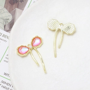 Detailed close-up of pink bow charms with pearl accents for DIY jewelry making