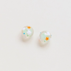 Macro shot of two transparent resin beads with stars and clouds for DIY crafts