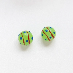 Dettaglio di due perline verdi da 16mm con puntini blu e motivi a spirale marrone scuro