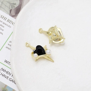 Detailed view of gold alloy charms featuring heart black gemstone and white pearls