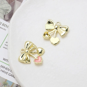 Detailed view of bowknot and heart charms with pink enamel for DIY jewelry making