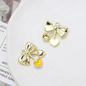 Detailed view of gold bow pendant with yellow enamel heart charm for DIY jewelry
