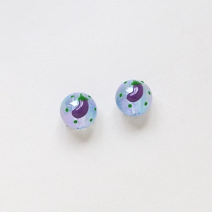 Dettaglio macro di perline azzurre da 16 mm con motivi di melanzane viola e pois verdi