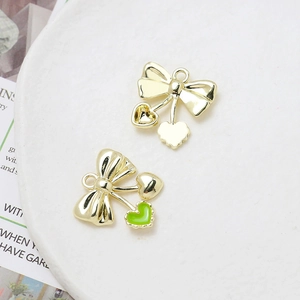 Detail of golden bow charms with heart pendants and green enamel for jewelry DIY