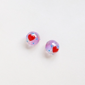Vista macro di perle tonde in acrilico viola con pois blu e dettaglio cuore rosso 16mm