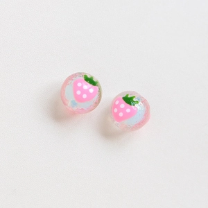 Detailed view of pink strawberry beads with ice-crack texture and white dots for DIY jewelry