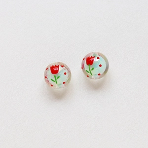 Detailed view of clear round beads with hand-painted red tulip patterns for DIY jewelry