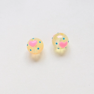 Dettaglio macro di perle iridescenti da 16mm con cuori rosa e pois blu per gioielli