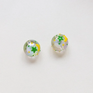 Dettaglio di perle olografiche da 16mm con stelle verdi, lune gialle e pois decorativi