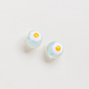 Close-up of handmade light blue tulip beads with a cute fried egg design for DIY jewelry
