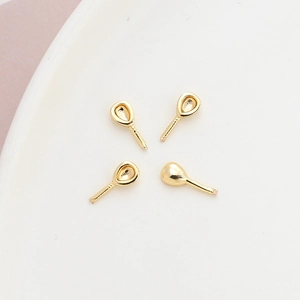 Macro detail of four gold-plated pearl cup settings on a white ceramic tray for DIY jewelry