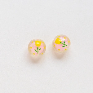 Macro shot of pink translucent beads with hand-painted yellow tulips and green leaves