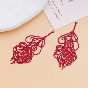 Close-up of red hollow metal peacock feather charms for DIY jewelry and hair accessories