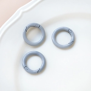 Three matte grey O-ring spring clasps displayed on a white tray for DIY crafts