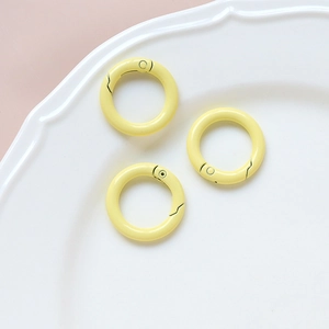 Three bright yellow spring gate rings for DIY accessories on a white ceramic plate