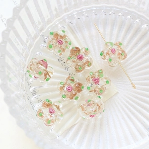 Macro detail of plum blossom glass beads with gold glitter and pink rose center for DIY jewelry