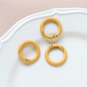 Three bright yellow spring O-rings for DIY crafts placed on a textured white ceramic plate