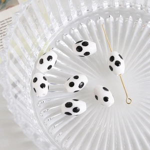 Macro detail of oval white ceramic beads with black polka dots on glass tray