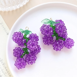 Dettaglio di ciondoli a forma di uva viola in perline fatti a mano su vassoio bianco